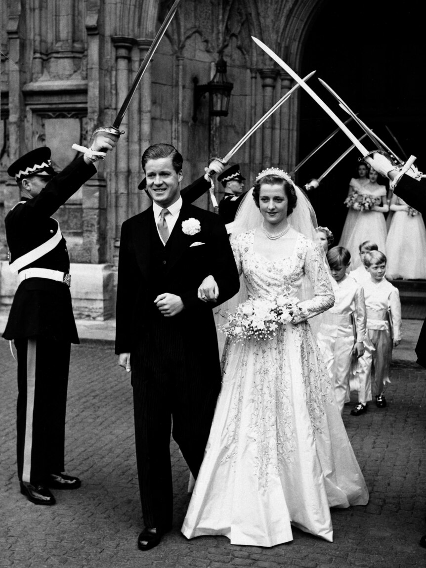 A black and white photo of a bride and groom walking out of a church 