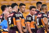 Brisbane Broncos NRL players look dejected as they stand in a group next to goal posts against the Sydney Roosters.