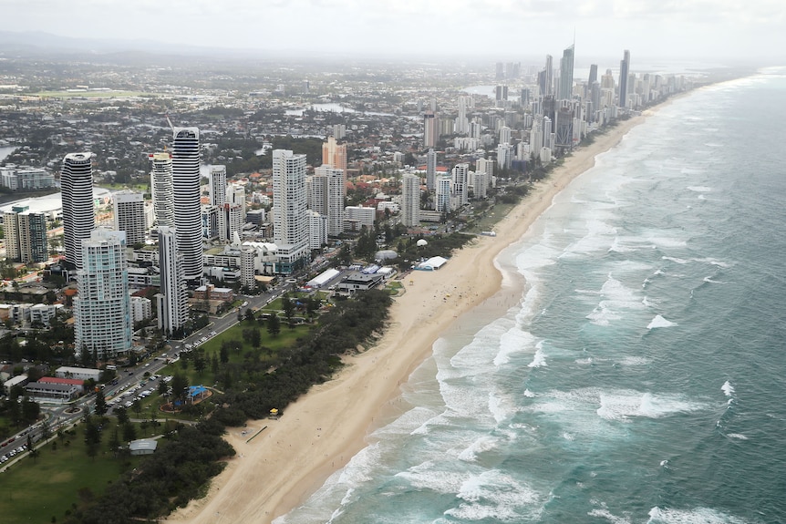 An aerial view of tall skyscrapers beside a sandy coast