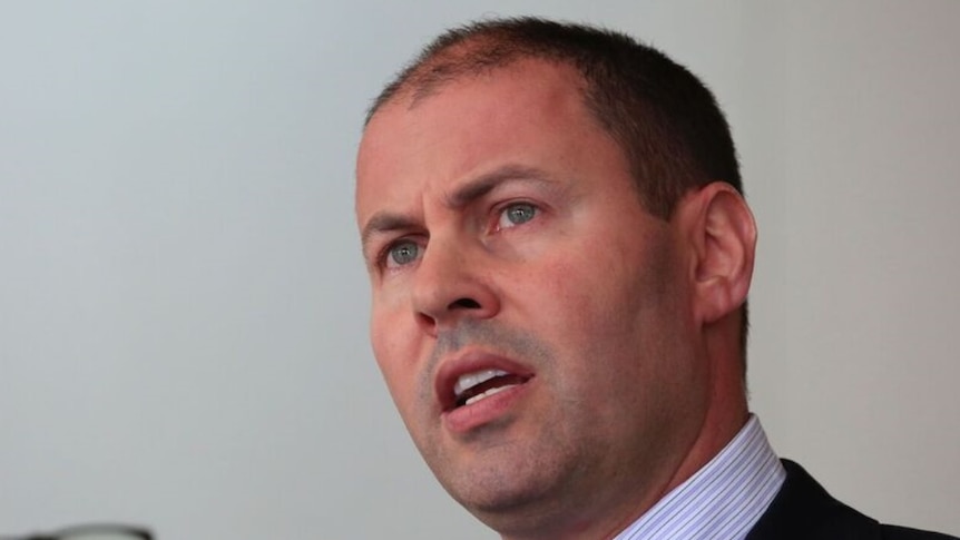 Josh Frydenberg, shot from slightly below, speaks at a press conference. He has a sincere expression on his face.