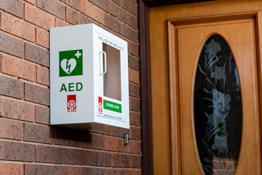 A white box with a defibrillator in front of a home