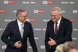 Albanese straights his jacket while laughing, Morrison pulls an awkward thumbs up