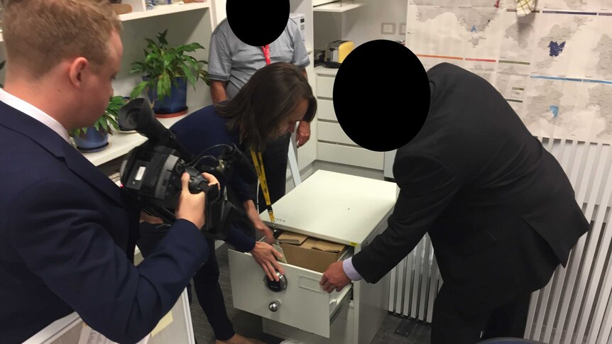 Files are locked away in a white safe. ASIO staff are present, and their faces are blacked out for legal reasons.