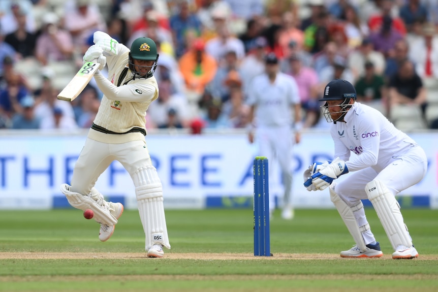 Usman Khawaja is on his back foot as he punches the ball into the off side as Jonny Bairstow watches on