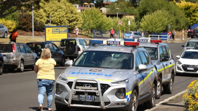 A row of police cars line a street outside Hillcrest Primary School in Devonport.