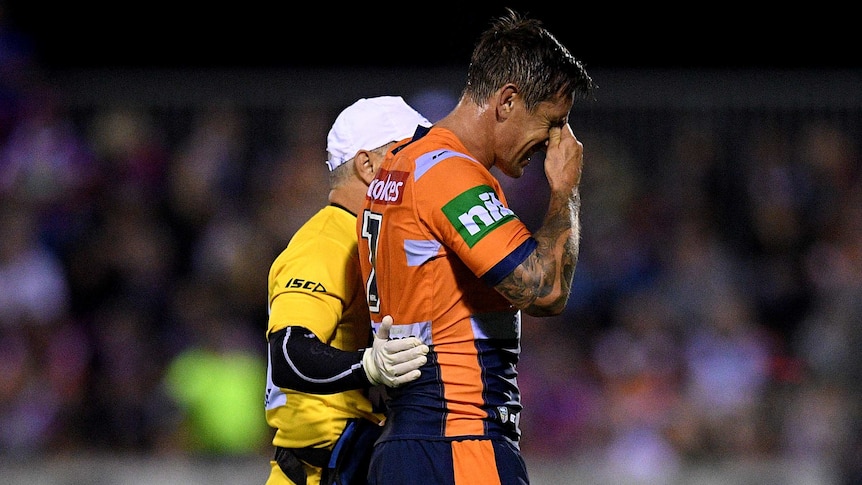 Mitchell Pearce of the Knights is assisted from the field by a trainer against Wests Tigers.