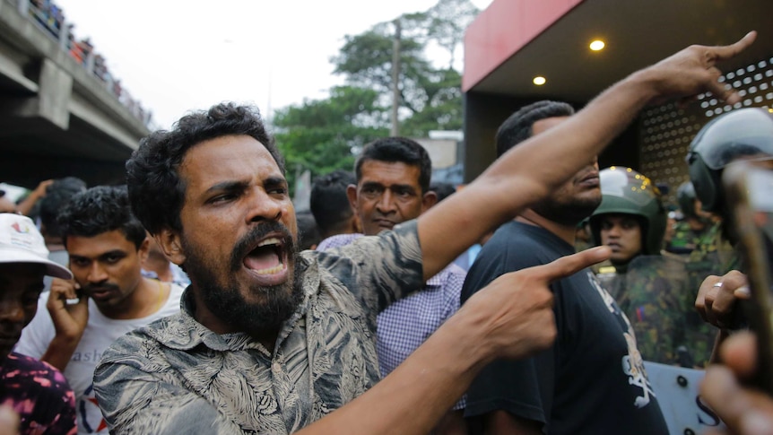 A supporter of newly appointed Sri Lankan prime minister Mahinda Rajapaksa shouts at police officers.