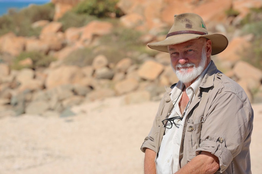 A man in a hat standing in the rocky Pilbara.