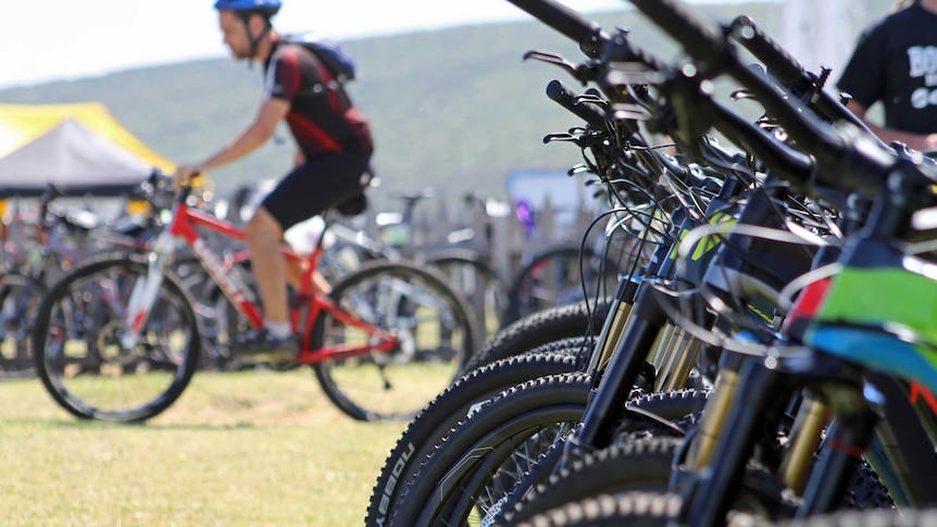 A man on a mountain bike, with a row of bikes to his right.