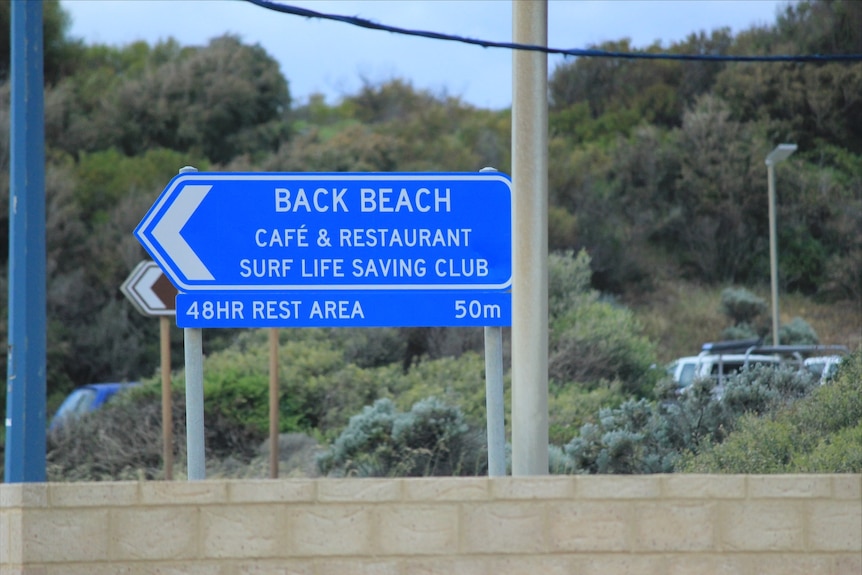 A blue road sign reading Back Beach cafe and restaurant, surf life saving club, 48hr reset area 