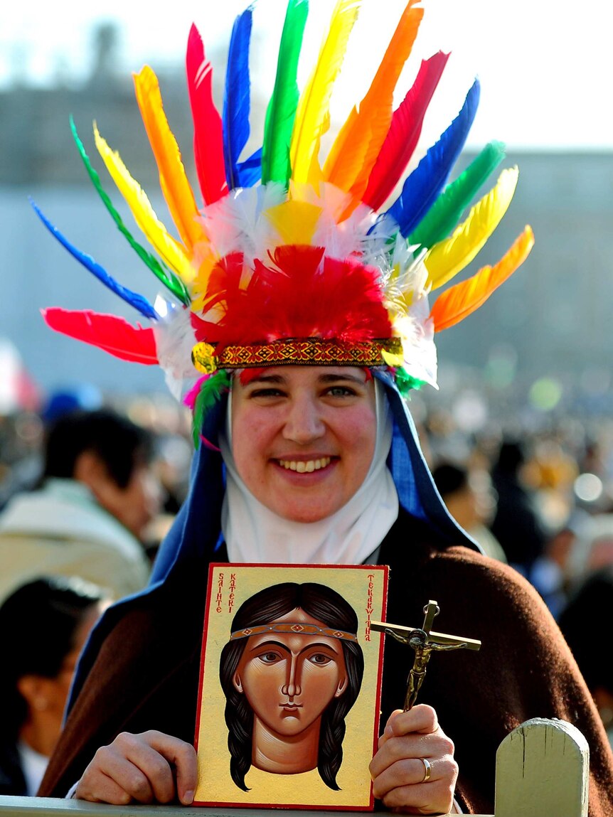 A member of the faithful holds a painting representing Kateri Tekakwitha.