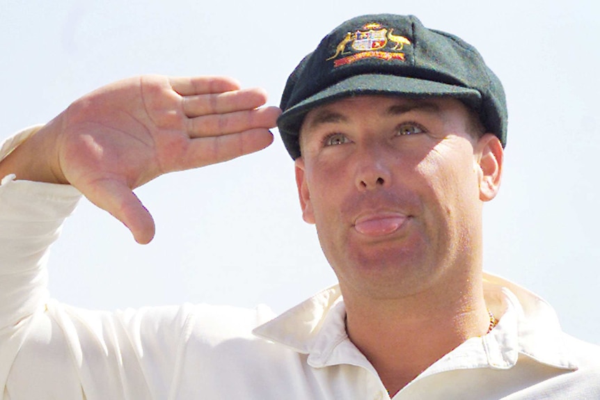 Shane Warne salutes while poking out his ton and wearing his baggy green