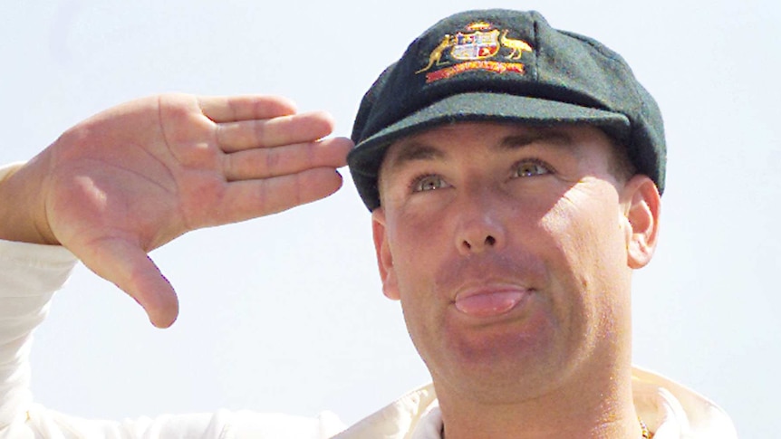 Shane Warne salutes while poking out his ton and wearing his baggy green