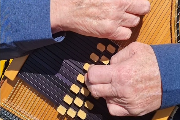 Hands on a wooden instrument, an autoharp.