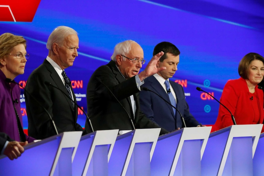 All of the democratic candidates standing in a line behind lecterns