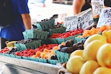 Fruit and vegetables for sale with man wearing backpack browsing