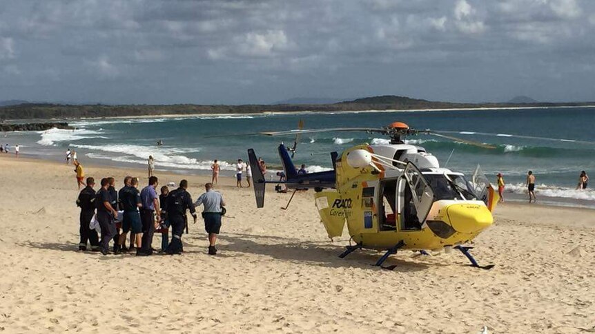 Paramedics carry the pilot on a stretcher to a helicopter