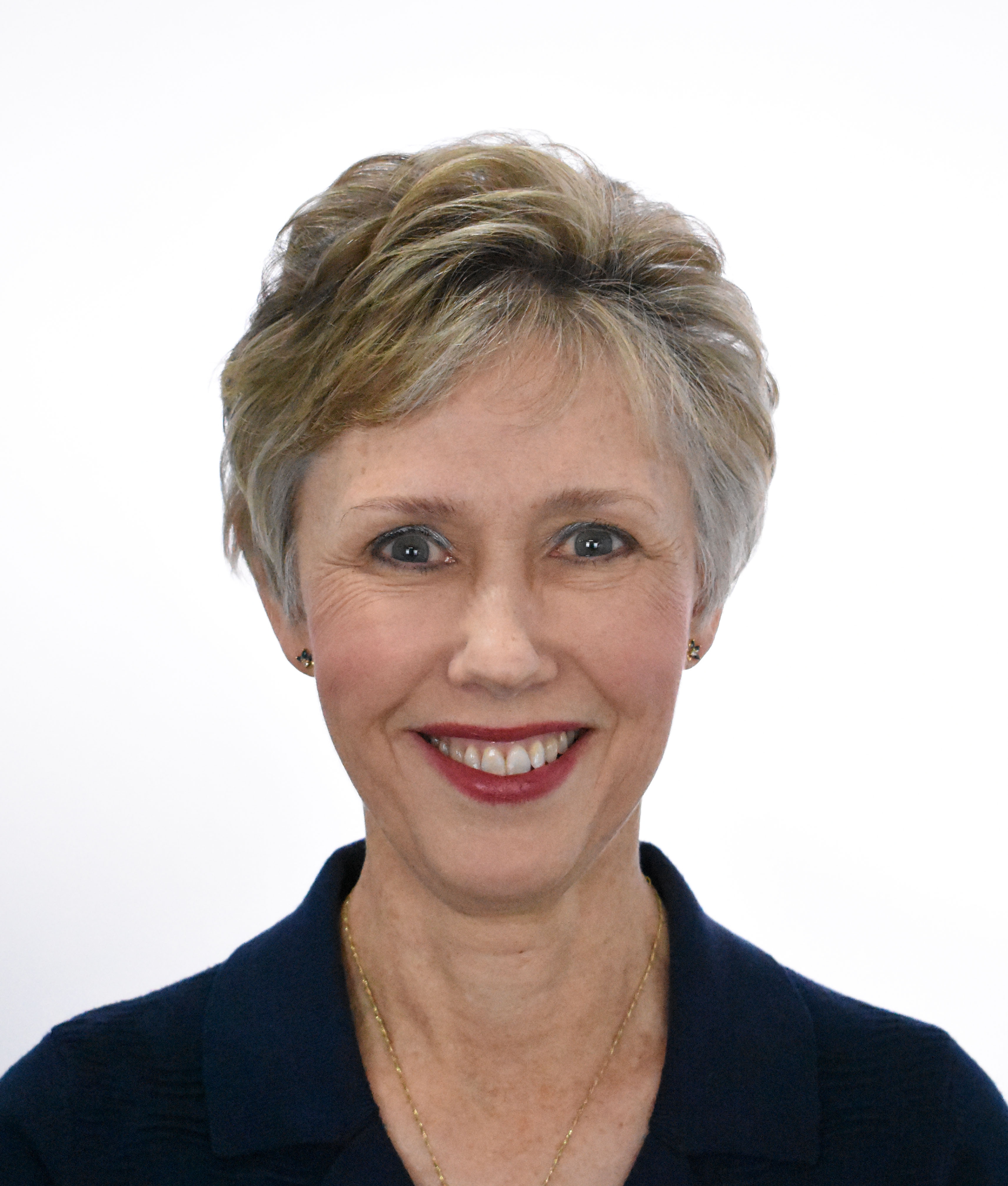 A smiling Caucasian woman with short ash blonde hair, wearing red lipstick and a black shirt.
