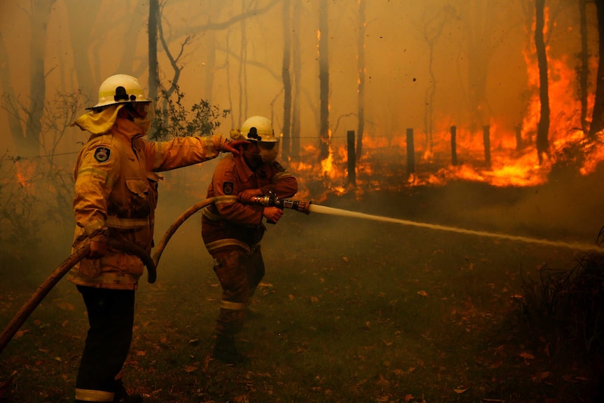 two firefighters battle a fire