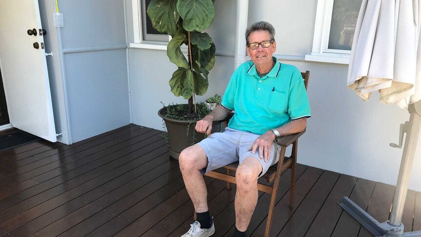Graham Leask sitting in a wooden chair on the back deck of his Ipswich property