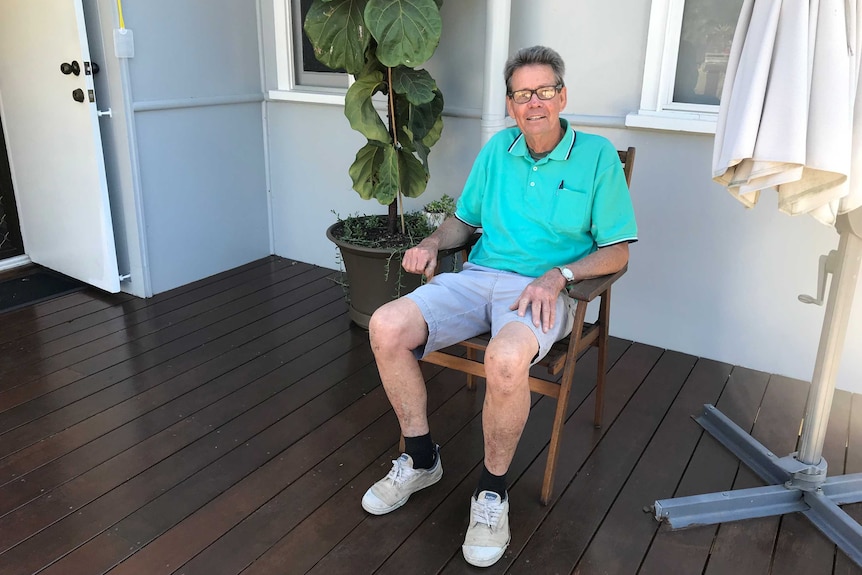 Graham Leask sitting in a wooden chair on the back deck of his Ipswich property