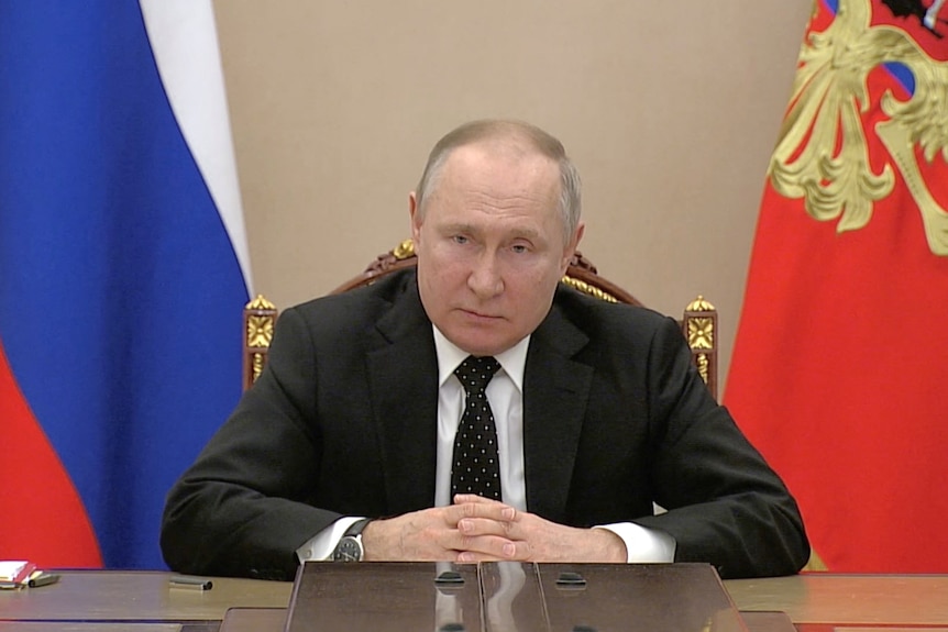 Russian President Vladimir Putin seated.