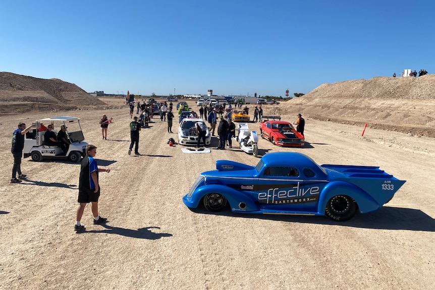 Cars and people on a dirt track