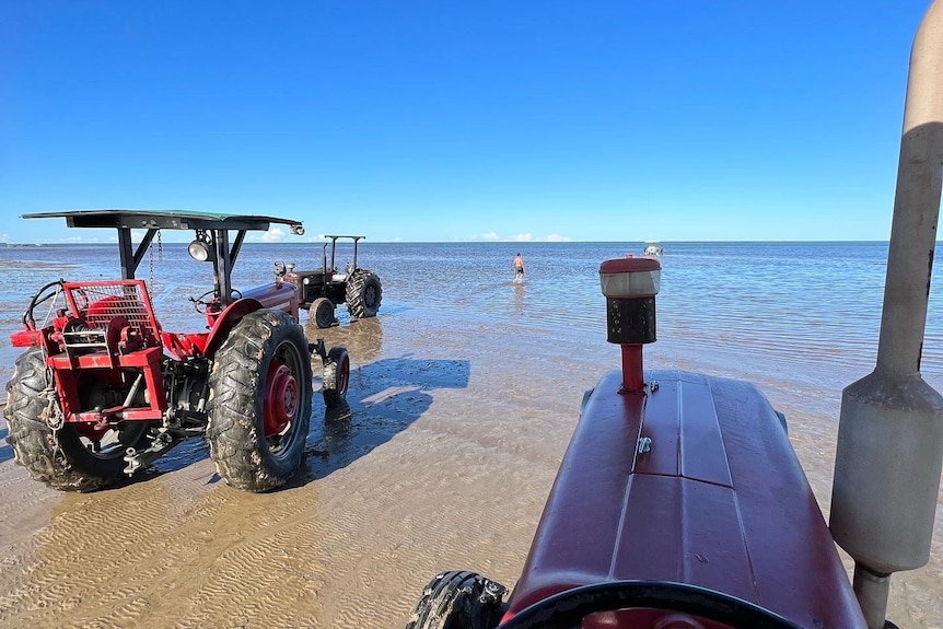 Two tractors bogged on a sandy beach