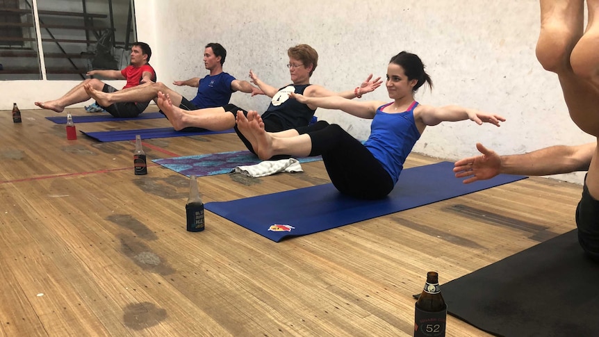 A class of people practice yoga with beers