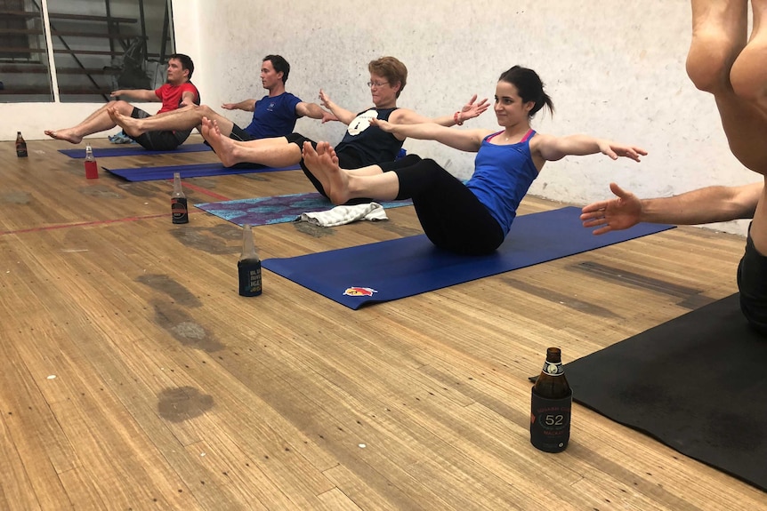 A class of people practice yoga with beers