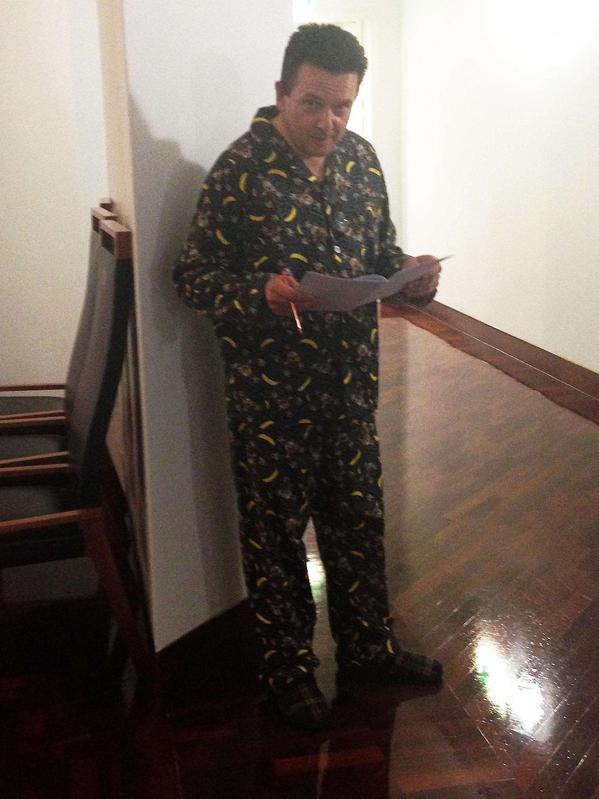Senator Nick Xenophon wearing flannel pyjamas while poring over documents in the halls of Parliament House