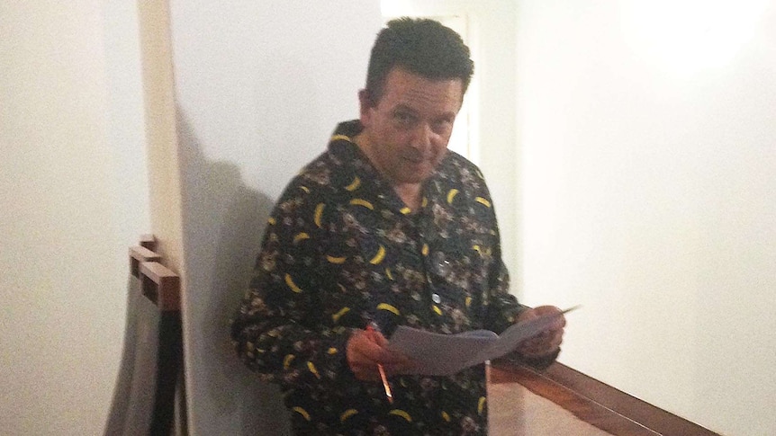 Senator Nick Xenophon wearing flannel pyjamas while poring over documents in the halls of Parliament House