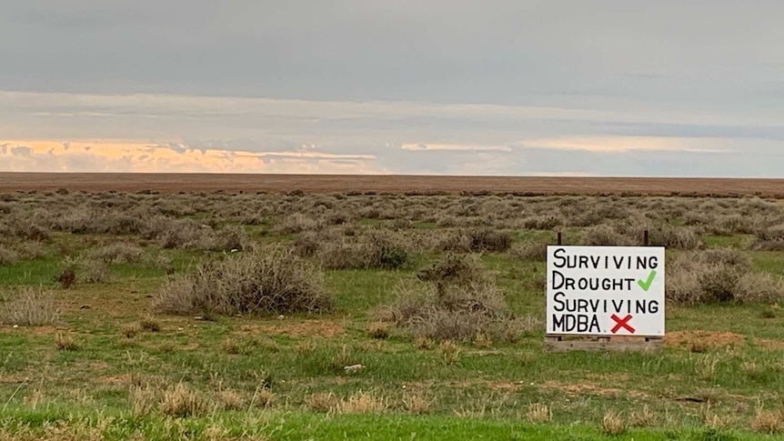 A poster which blames the water authority, not the drought, sits in an empty paddock outside Deniliquin.