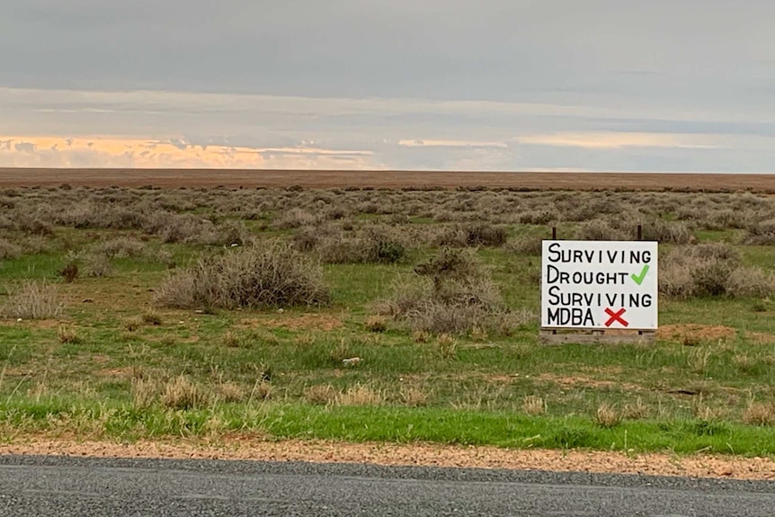 A poster which blames the water authority, not the drought, sits in an empty paddock outside Deniliquin.