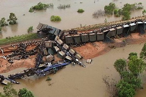 A freight train lies in pieces in floodwaters.