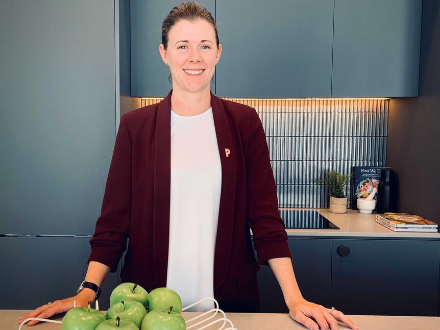 Hannah stands in a stylish kitchen, smiling.