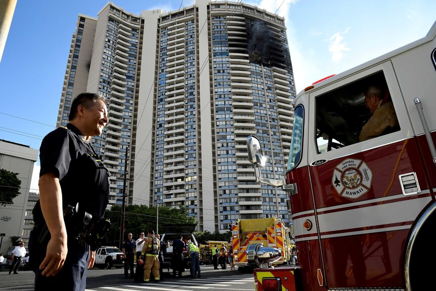 A police officer directs a fire truck at the Marco Polo apartment building after a fire broke out in it in Honolulu,