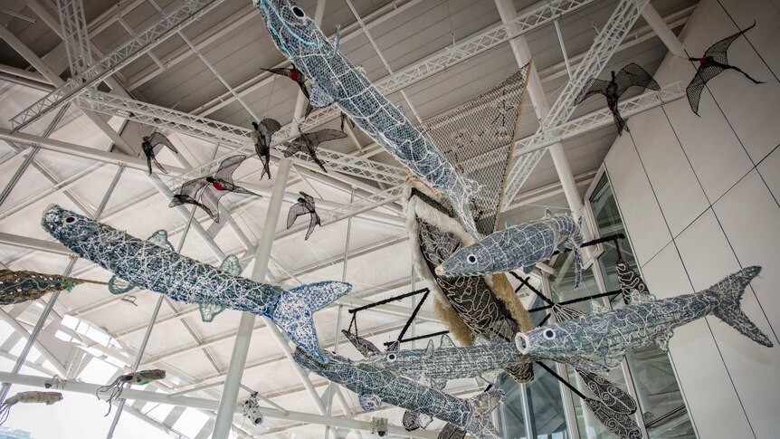 Large sea creatures made of fishing nets suspended from museum ceiling