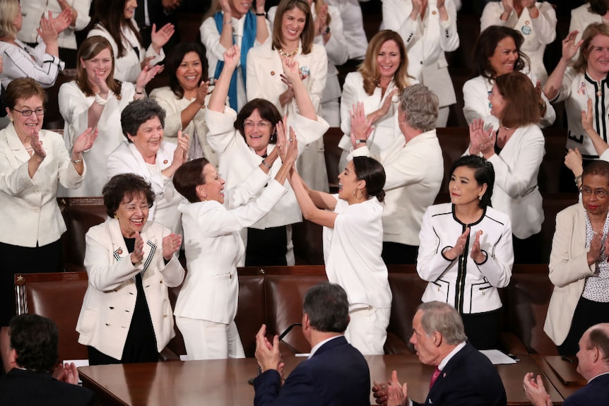Women wearing white cheering and high-fiving each other.