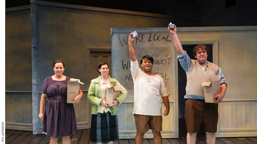 Four actors on a stage, two women holding boxes and two men holding ice cream tubs in the air