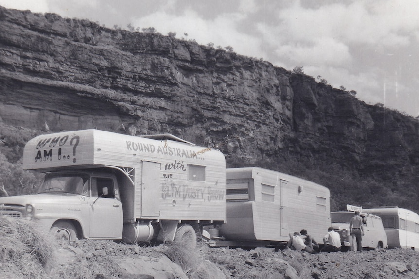 A black-and-white photo of a caravan convoy on a steep rocky road.