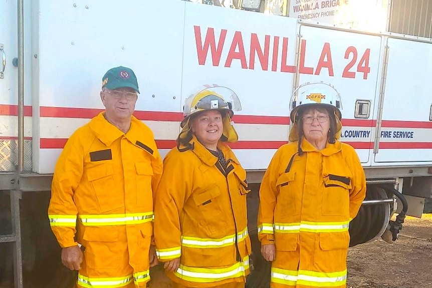 Three people in orange uiniforms in front of white truck with Wanilla sign on it.