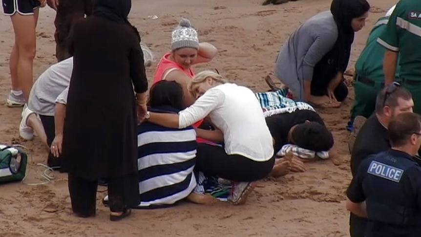 Paramedics work on the beach after five people rescued from the water at Petrel Cove.