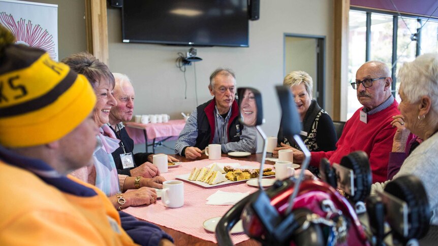 Customers sit around a table at a dementia cafe
