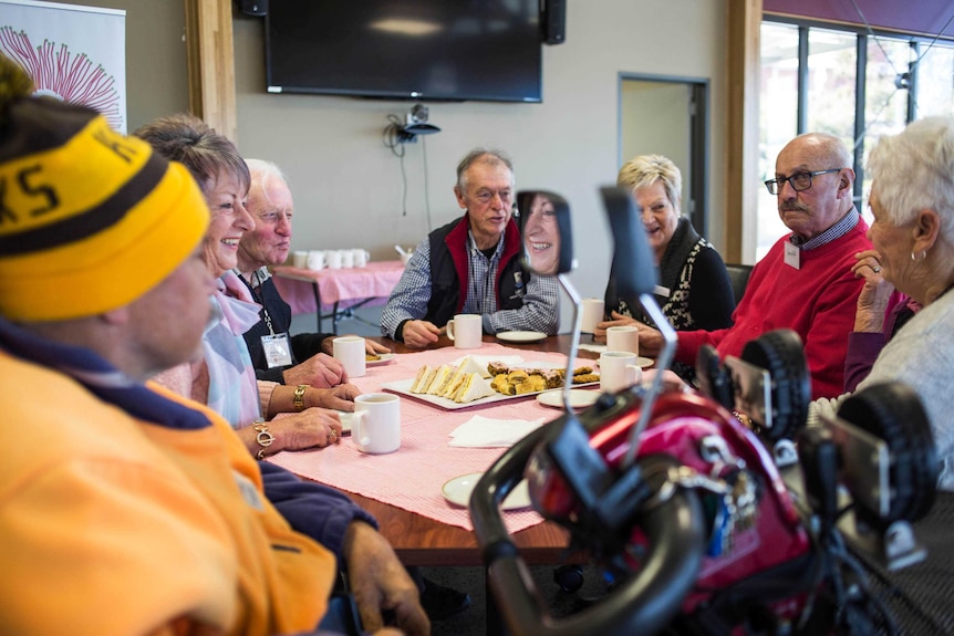 Customers sit around a table at a dementia cafe