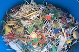Plastic sticks and other debris in a blue bucket