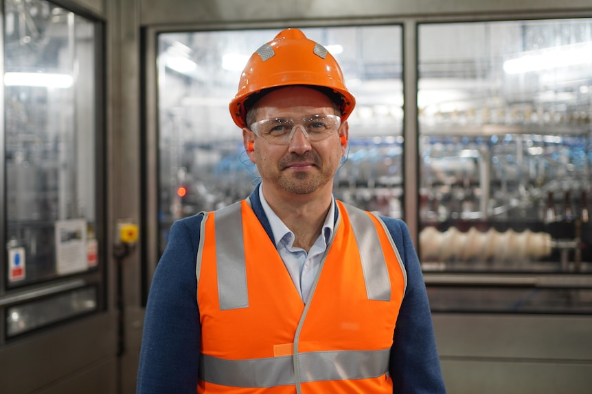 A man in hi-vi vest, helmet and protective glasses inside a processing plant