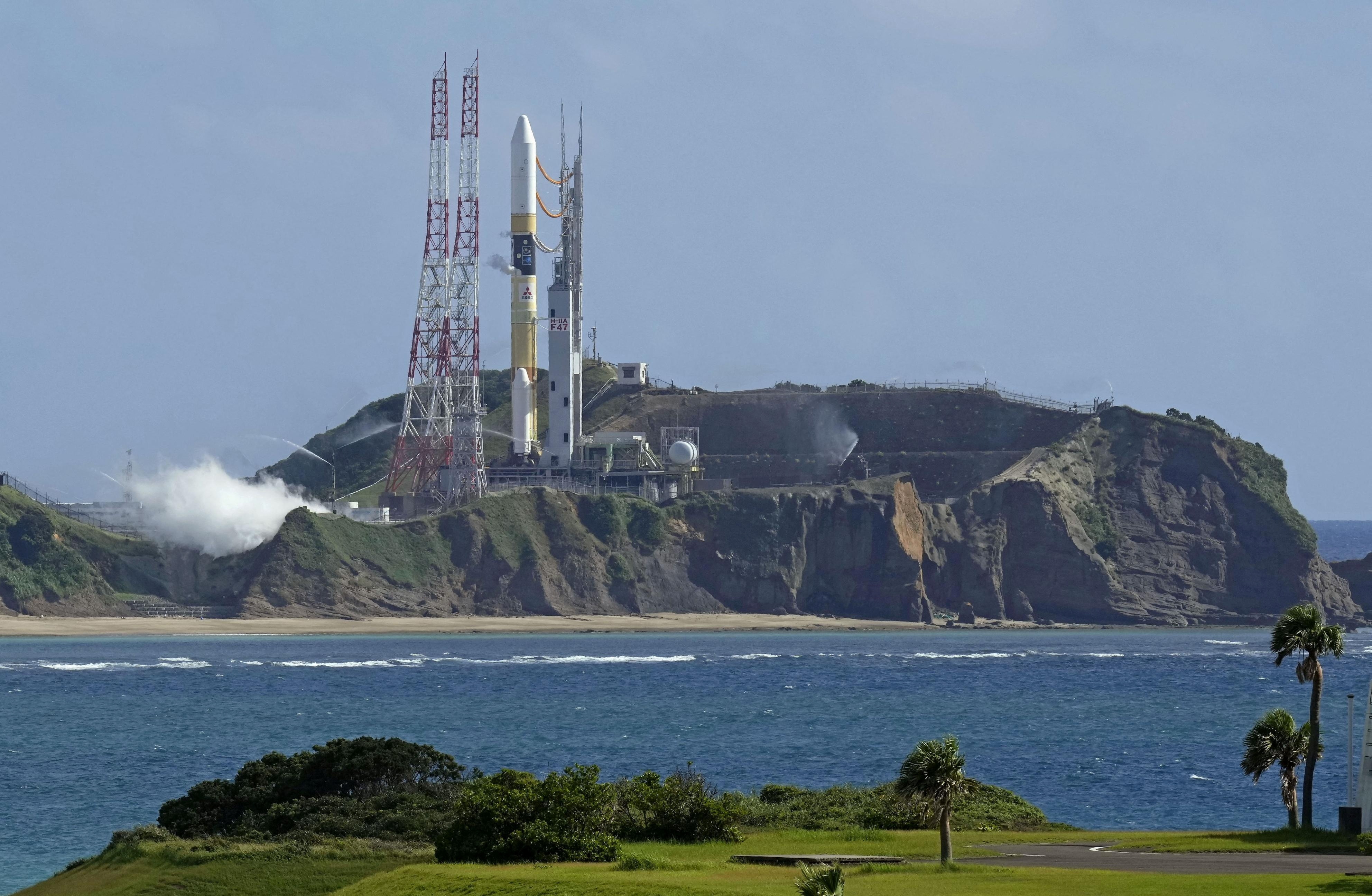 A space rocket launch vehicle on a rocky island, the picture is taken across the water from the mainland
