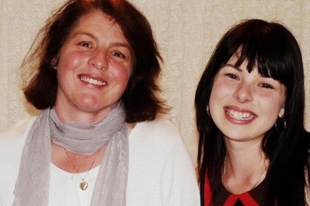 Two smiling, fair-skinned, dark-haired women with similar facial features posing for a photo.