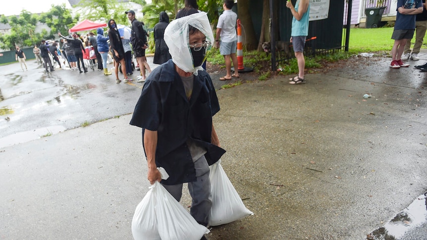 A resident carrying sandbags from a city run sandbag distribution location.